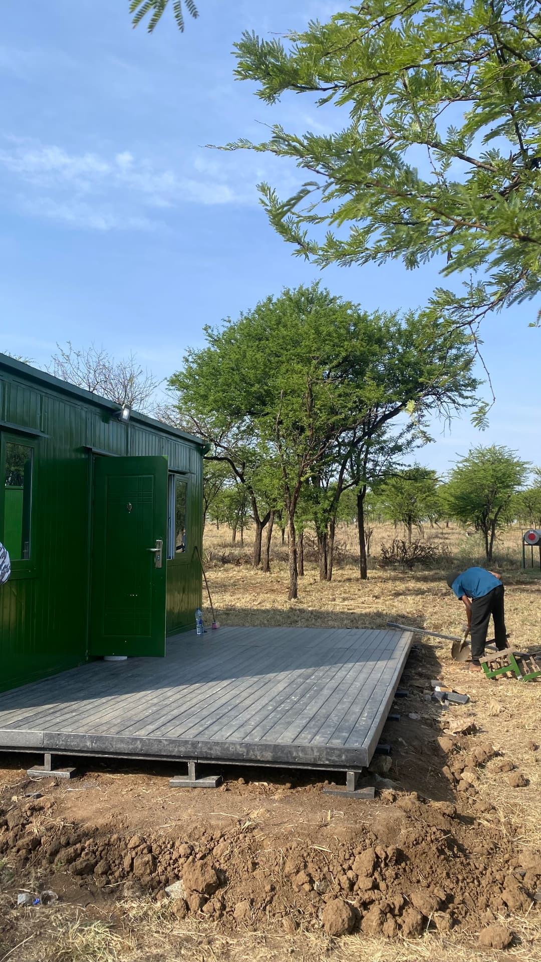 Recycled plastic deck laid on steel pedestals outside a green cabin at the Nyasa Balloon Safari base