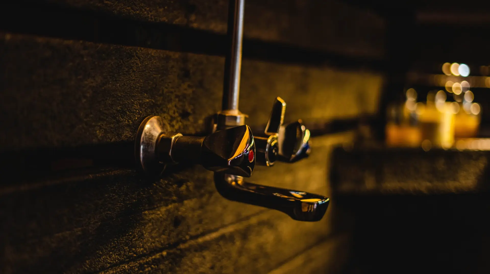 Close-up of a brass shower mixer mounted on dark recycled plastic cladding boards