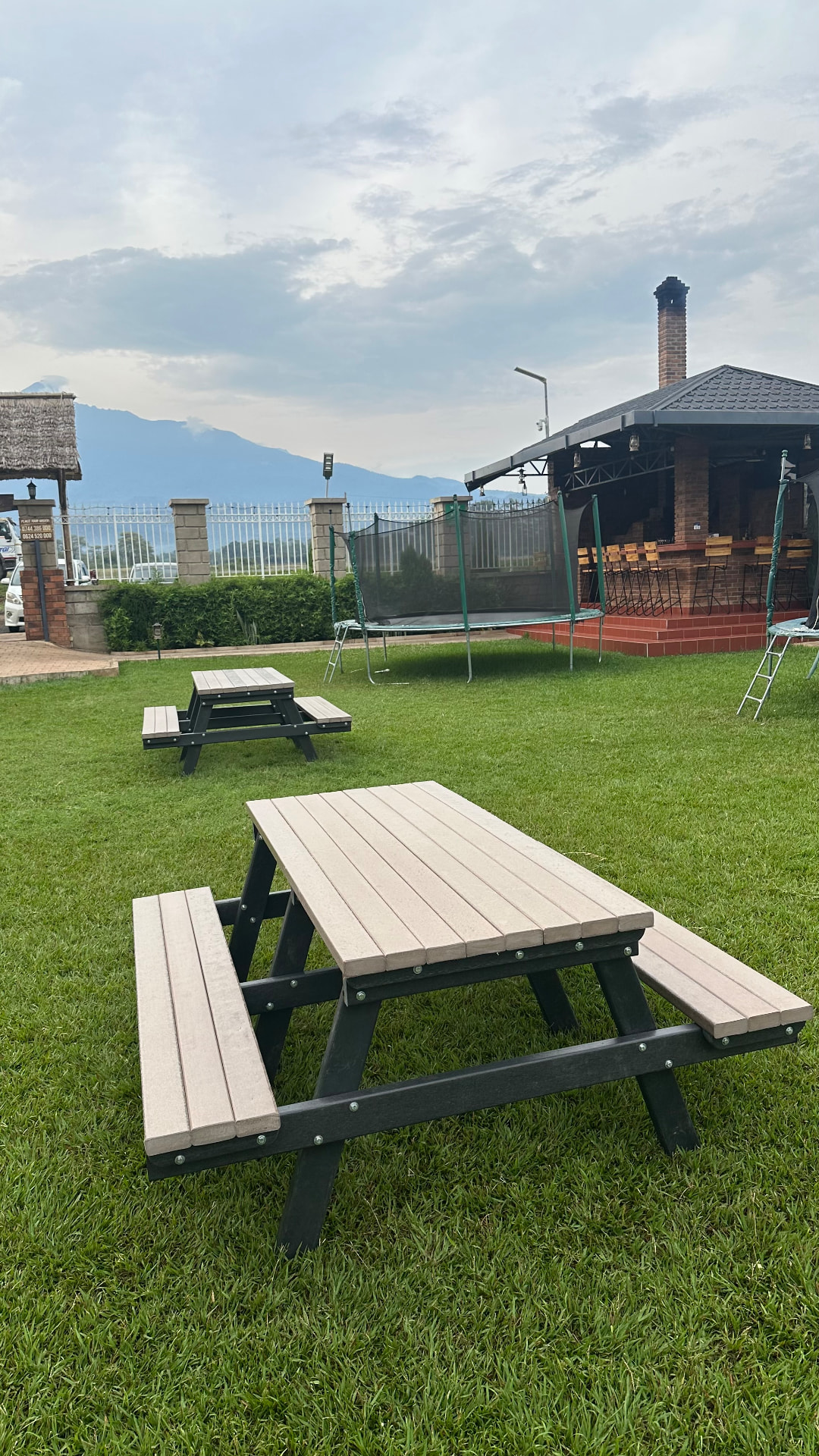 Recycled plastic picnic tables on a hotel lawn with Mount Meru in the background