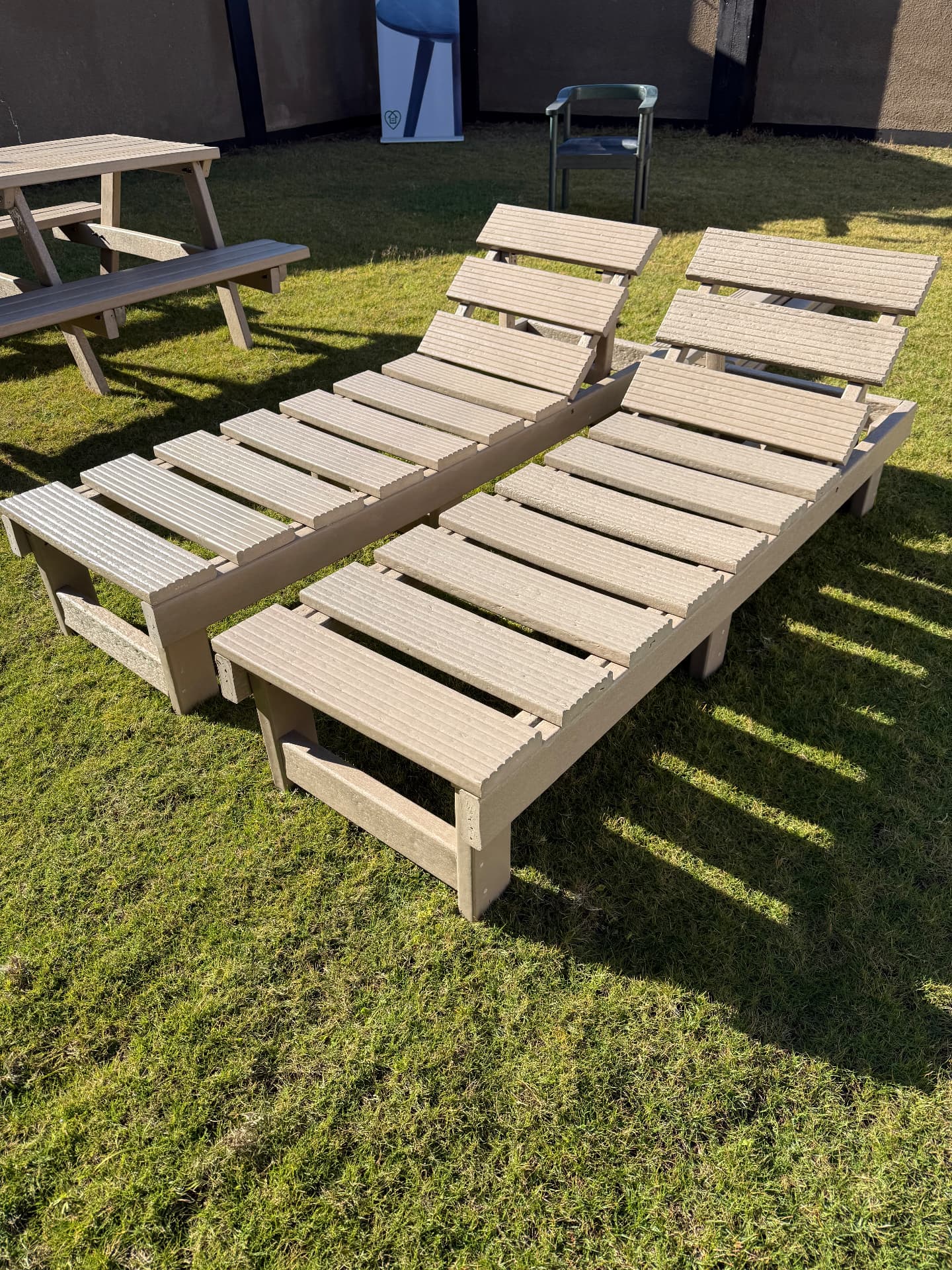 Recycled plastic sun loungers beside a lawn