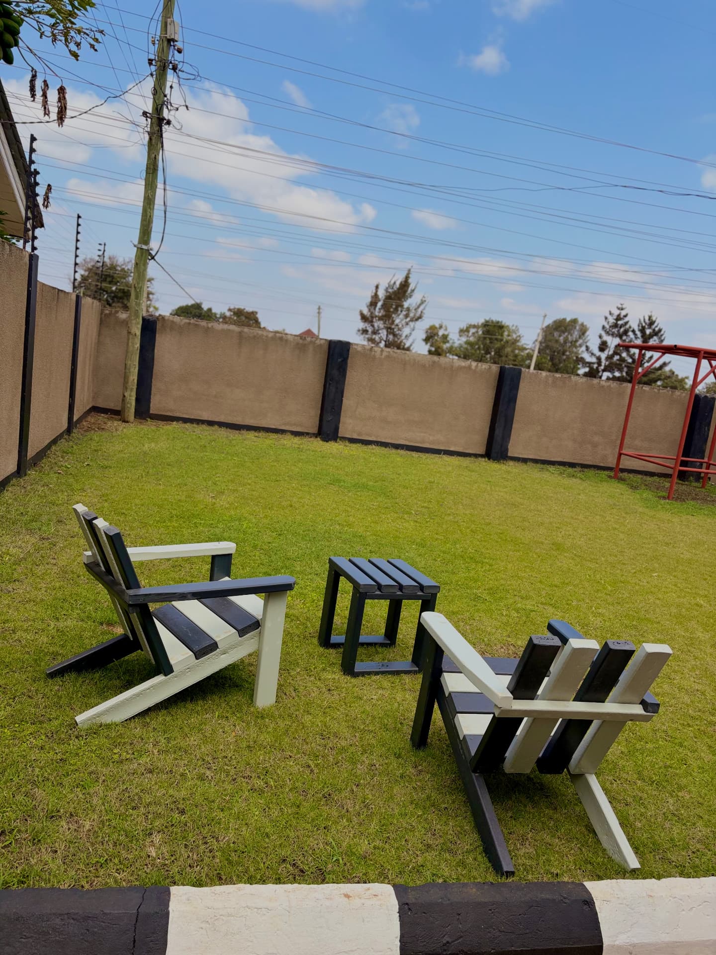 Black and cream recycled plastic garden lounge chairs with a matching side table on a lawn