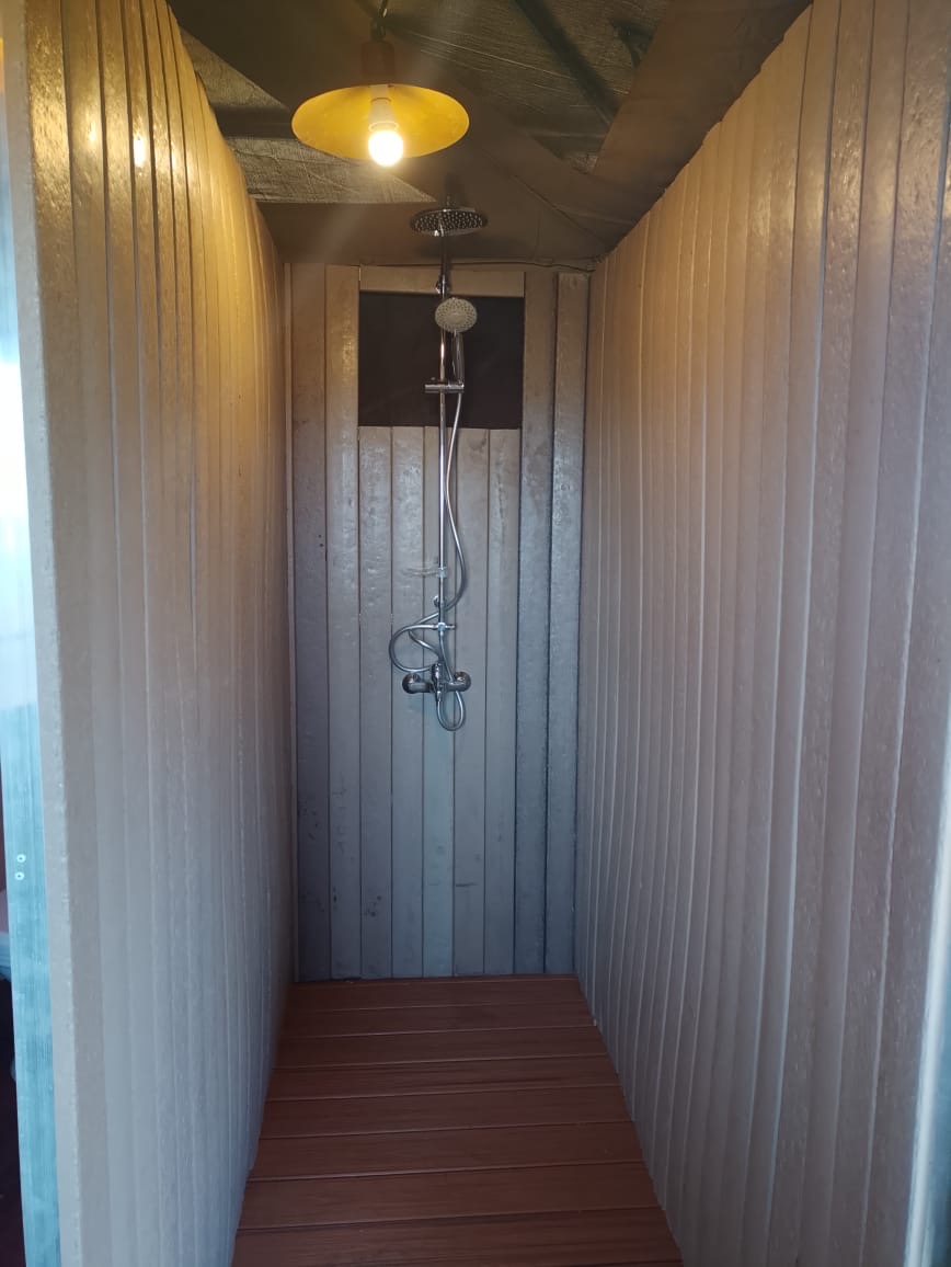 Tented camp shower room fully clad in recycled plastic boards with a recycled plastic floor