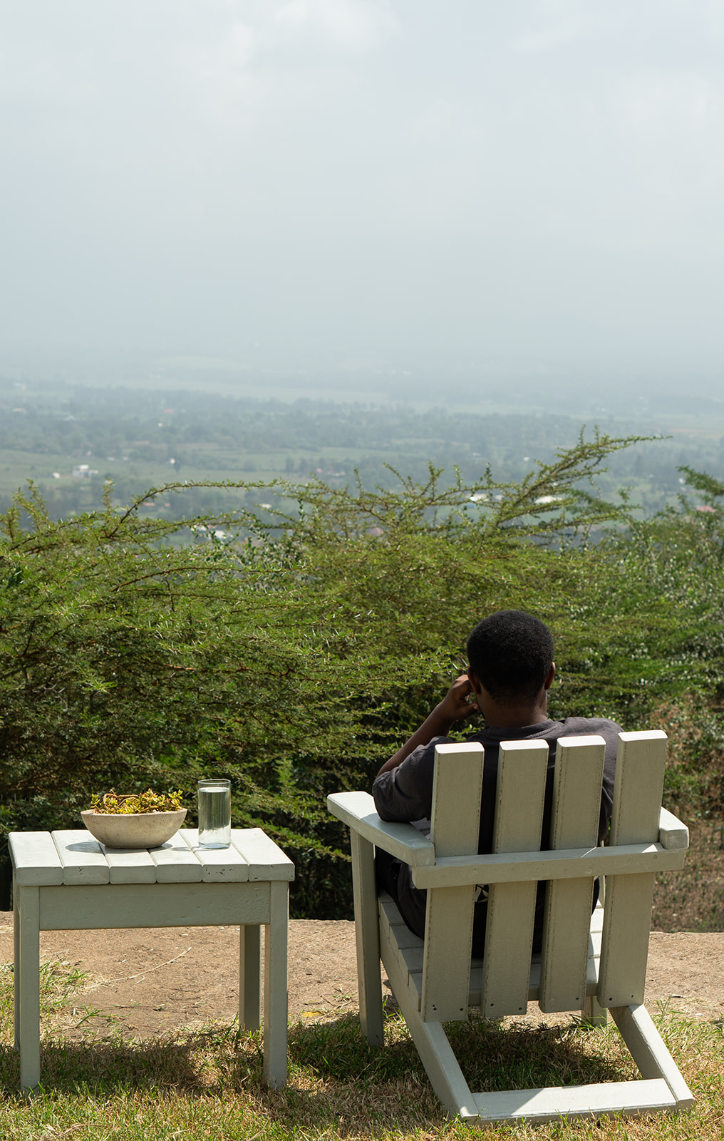 Man relaxing in a recycled plastic adirondack chair with side table overlooking the Arusha valley
