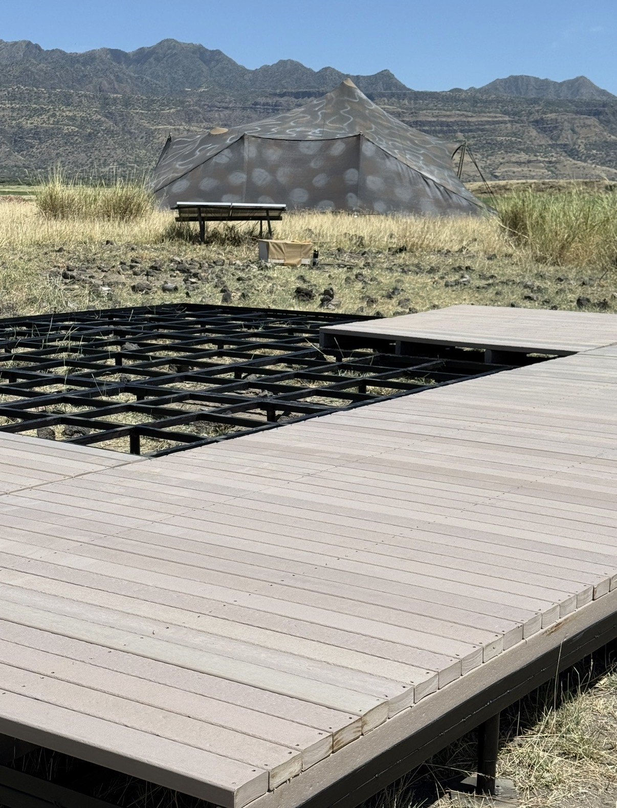 Recycled plastic deck boards installed on a safari camp platform with mountains beyond