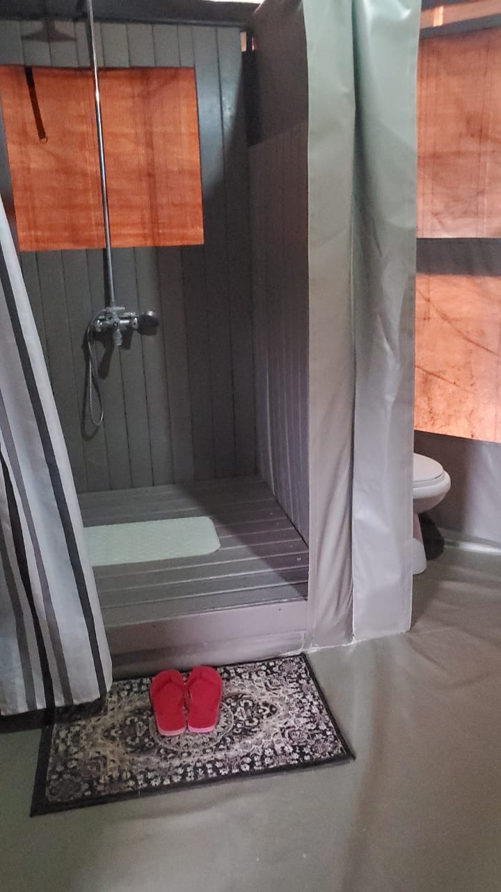 Recycled plastic cladding lining a tented camp shower cubicle including the floor and walls