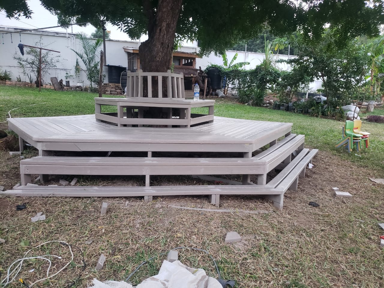 Recycled plastic tree deck with stepped perimeter benches in a garden setting