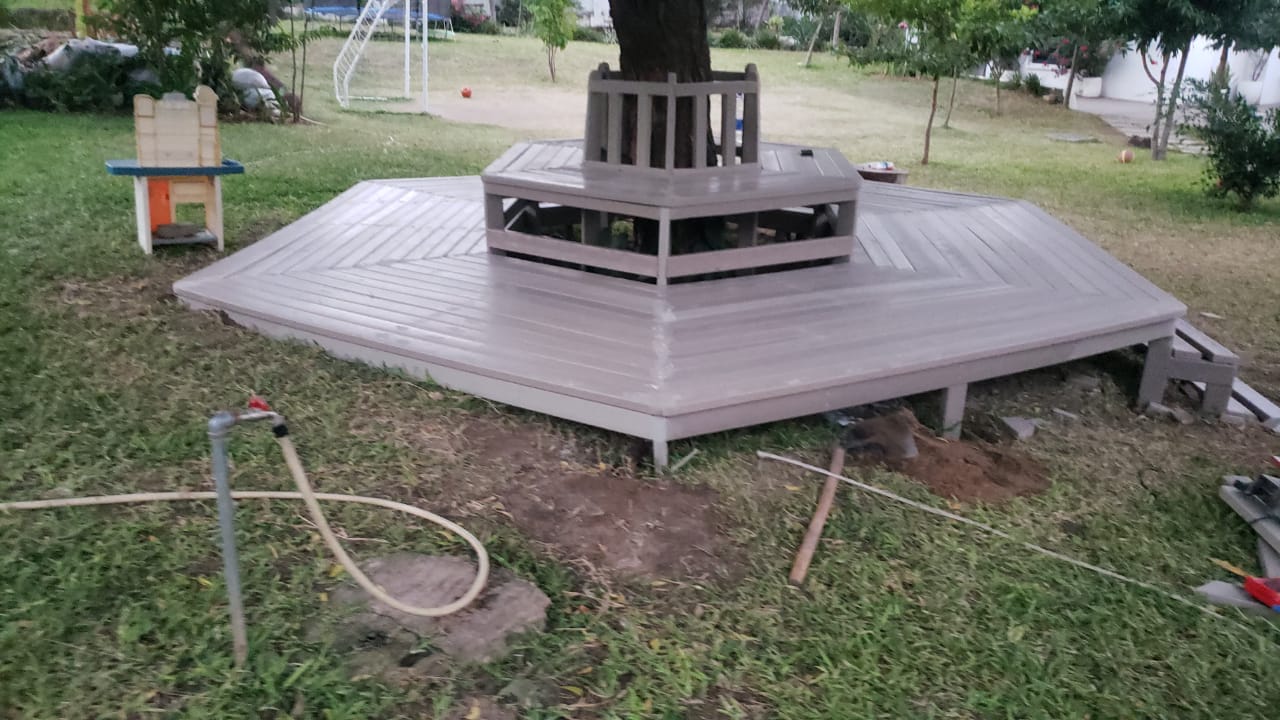 Hexagonal recycled plastic garden deck with integrated seating for a residential garden