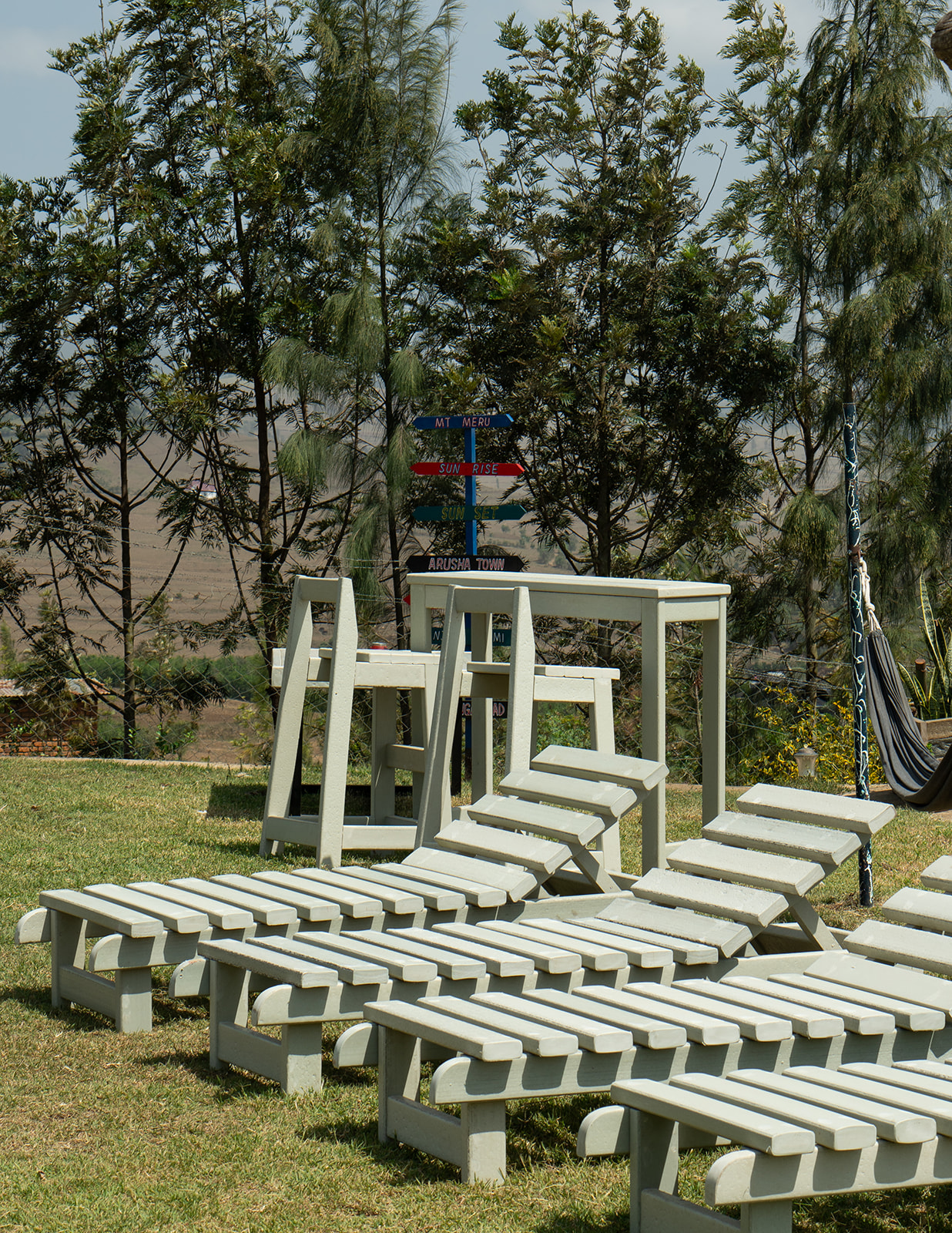 Light grey recycled plastic sun loungers and bar table on a lawn with signposts overlooking Arusha