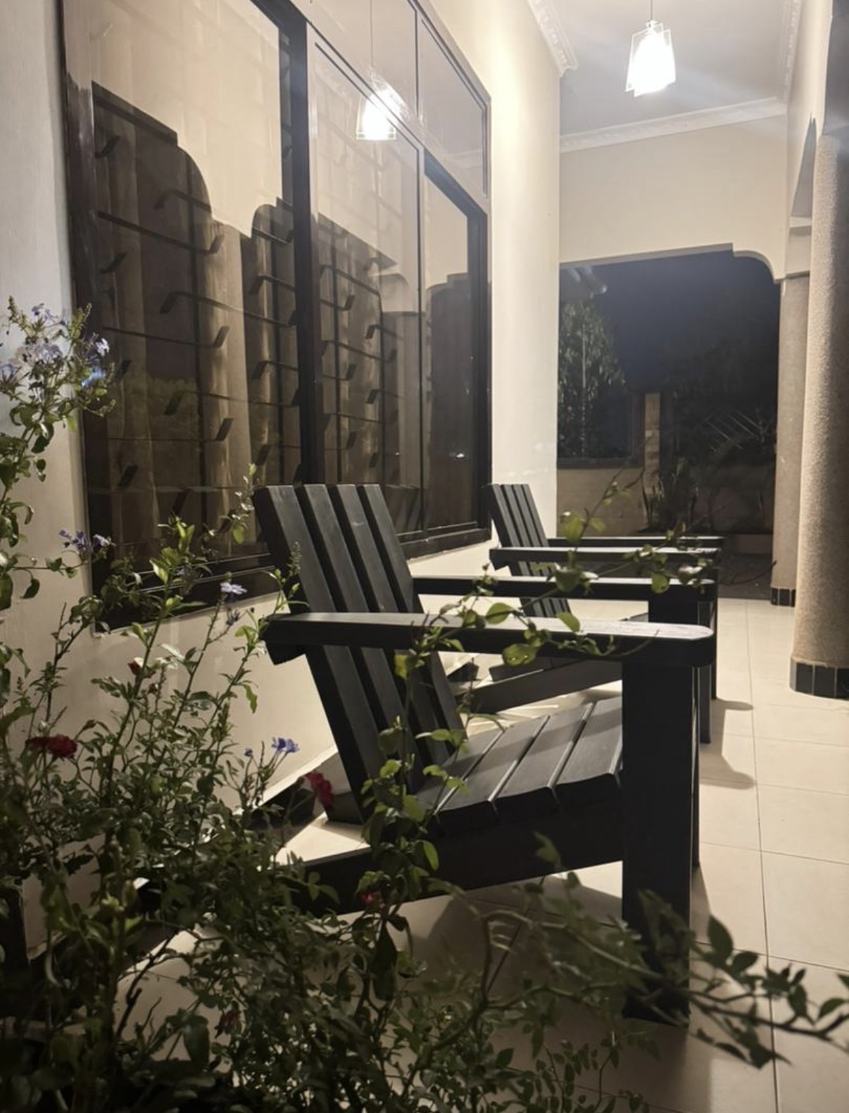 Black recycled plastic lounge chairs on a lit veranda at night